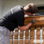 Hand met kwast brengt een laag Pullex Renovier-Grund aan op een houten oppervlak. 